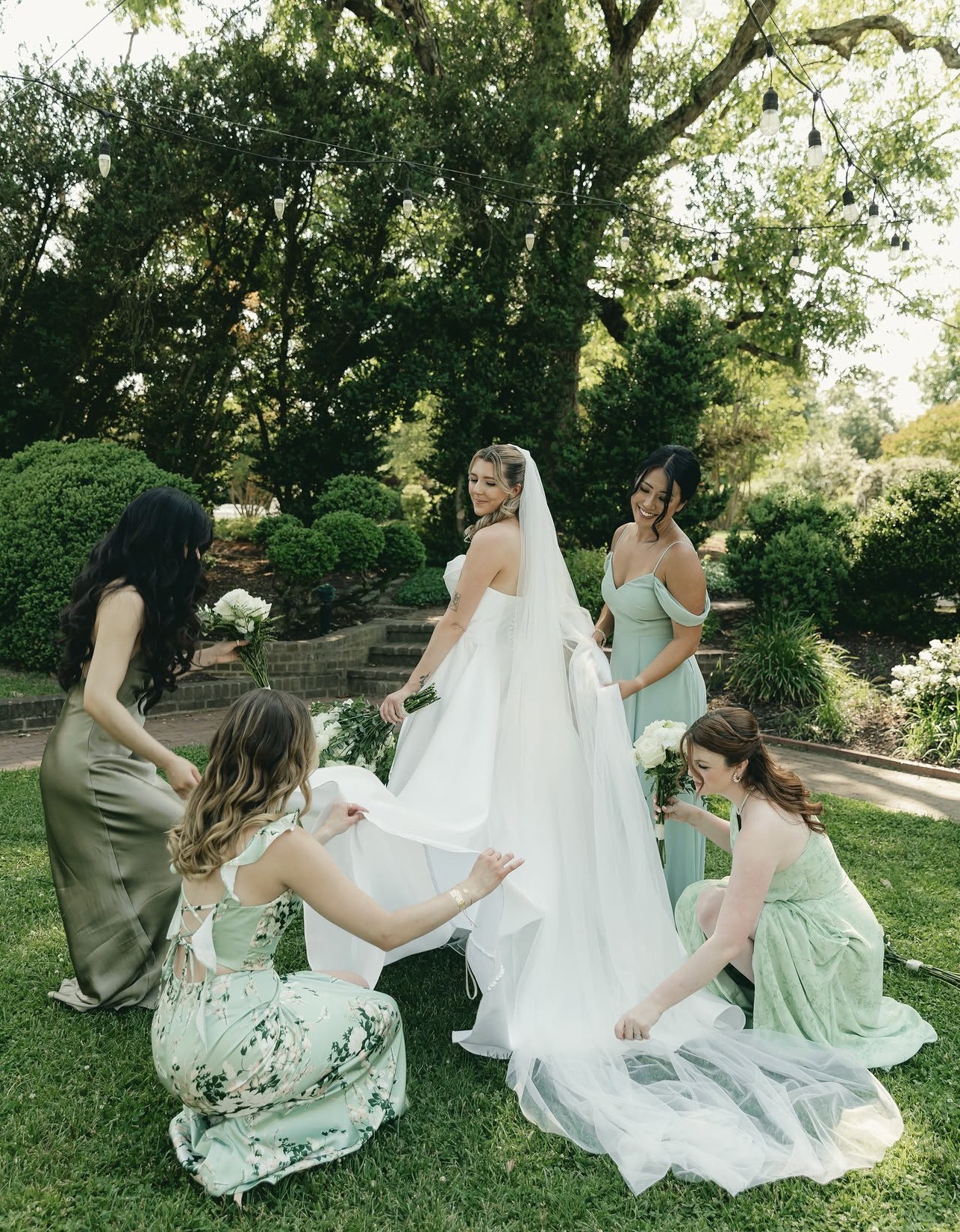 Bridesmaids helping the bride with her veil in the garden